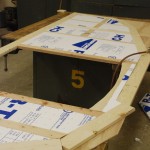 The insulation is cut and fit into place.  It doesn't need any glue as the fit is tight and it will be enclosed by the interior plywood.